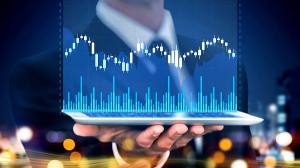 Empresário segurando tablet com gráfico financeiro digital de mercado de capitais, representando análise de investimentos e gestão de carteira.